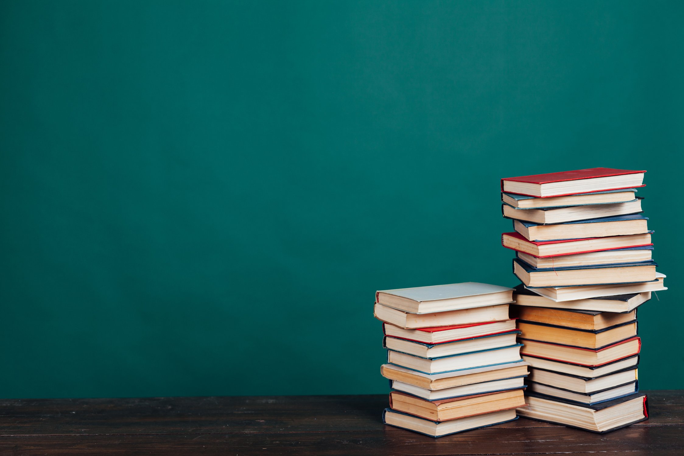 many stacks of educational books for learning preparation for college exams on a green background